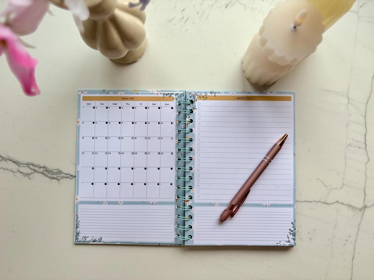 Open weekagenda 2027 met madeliefjes en een roségouden pen